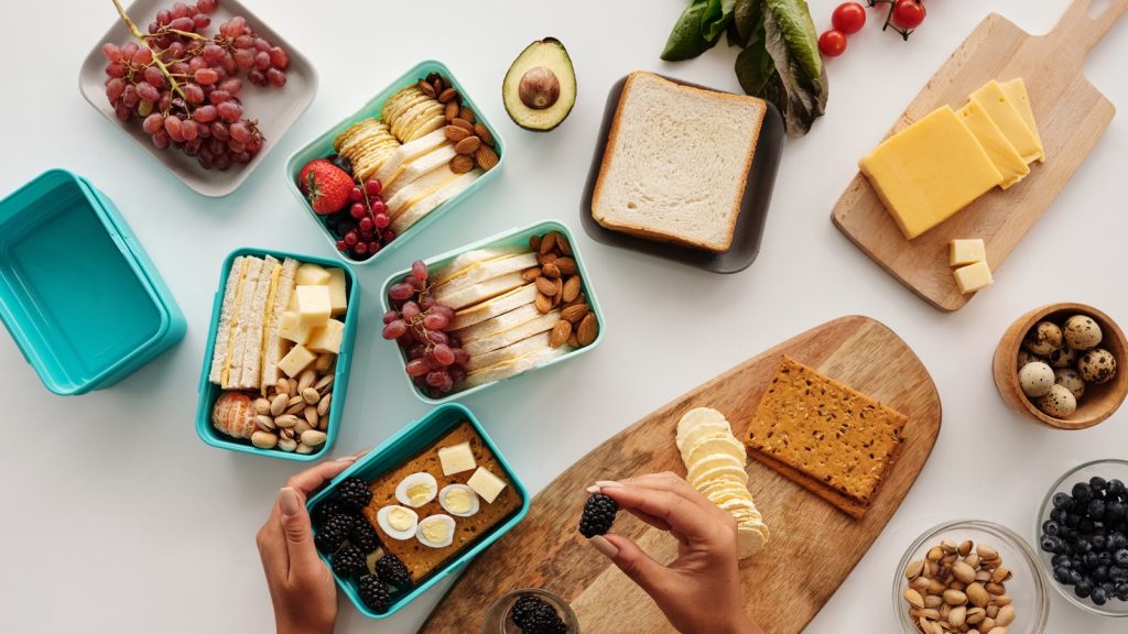 Madkasser pakket med sandwich, ost, nødder, bær og frugt